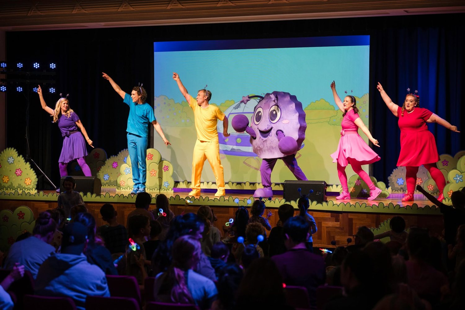 The five of us on stage at a live show, with the Bop Bop character and an audience of families